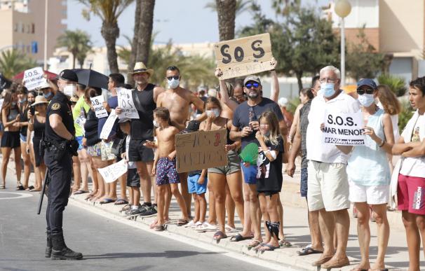 Varias personas participan en una protesta en defensa del Mar Menor al paso de la Vuelta Ciclista a España.