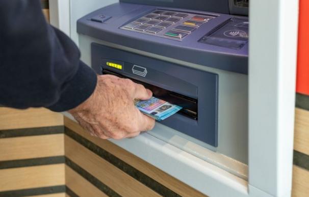 Una persona retirando dinero en efectivo de un cajero automático.