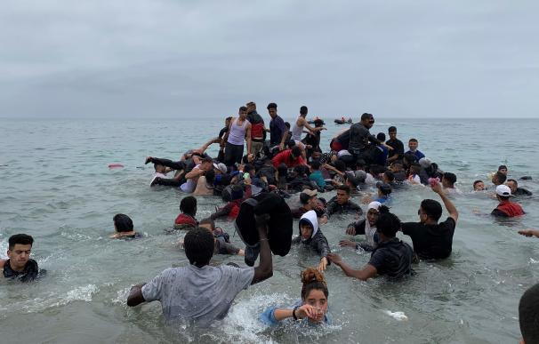 Un grupo de personas se hacen con una embarcación de las autoridades marroquíes en la playa de la localidad de Fnideq (Castillejos) para cruzar los espigones de Ceuta, el 18 de mayo de 2021, en una avalancha de inmigrantes sin precedentes en España al registrarse la entrada en 24 horas de 5.000 personas (un tercio de ellas menores).