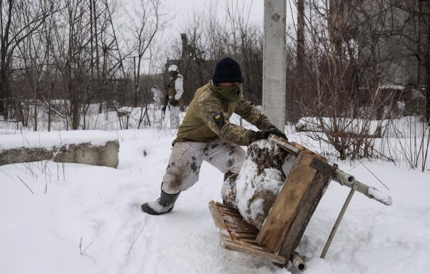 Donetsk (Ukraine), 25/01/2022.- Ukrainian serviceman stores up firewood on a front line near the Avdiivka village, not far from pro-Russian militants controlled city of Donetsk, Ukraine, 25 January 2022. US and Britain announced it is withdrawing some diplomats, nonessential personnel, and family members from their embassies in Kiev amid growing fears of a Russian invasion. Russia has recently strengthened its groups near the border with Ukraine and Belarus, with no signs of de-escalation, Pentagon spokesman John Kirby said on 24 January. (Incendio, Bielorrusia, Rusia, Ucrania, Reino Unido) EFE/EPA/STANISLAV KOZLIUK
