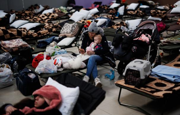 Una mujer con un bebé, en un centro comercial habilitado para los refugiados, en Mylny, a 27 de febrero de 2022, en Jaroslaw, Subcarpacia, (Polonia). Ucrania ha confirmado, por el momento, la muerte de más de 3.000 personas y según datos de ACNUR este domingo, la cifra de refugiados ucranianos asciende a 368.000 civiles, que han abandonado sus hogares en el país . Unas 150.000 personas han cruzado ya la frontera a Polonia. En su mayoría son mujeres y niños pues el gobierno de Ucrania prohíbe salir a los hombres de entre 18 y 60 años. Rusia ya ha entrado en Ucrania por varios flancos según el ejército ucraniano. El presidente del país, Volodímir Zelenski, se ha mostrado este domingo 27, abierto al diálogo con Rusia, pero ha rechazado hacerlo en Bielorrusia, por considerar a este país cómplice de la invasión que sufren. Alejandro Martínez Vélez / Europa Press 27/2/2022