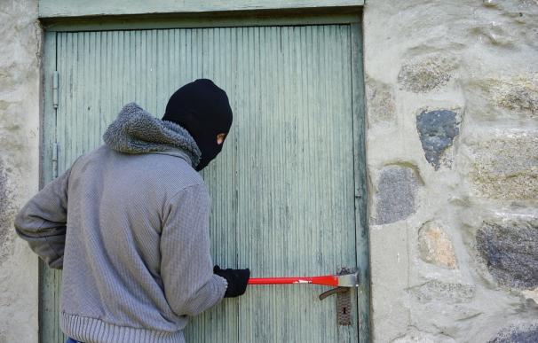 Un ladrón intentando entrar en una casa.