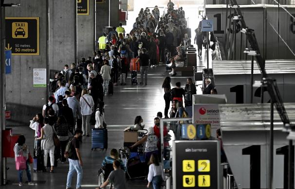 Decenas de personas hacen cola este miércoles para facturar el equipaje en el Aeropuerto de Barajas de Madrid.