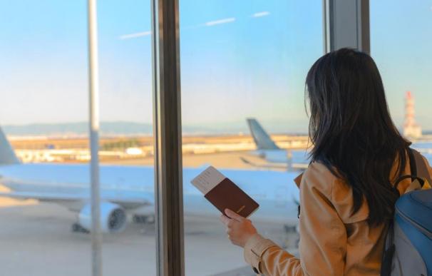 una chica en un aeropuerto mirando un avión antes de irse de viaje