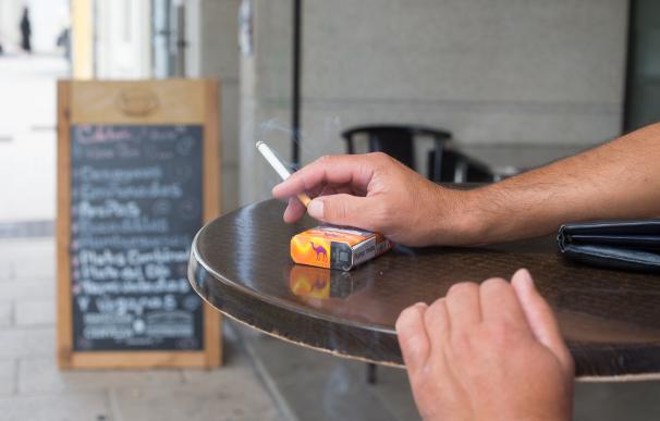 Un hombre sujeta un cigarrillo junto al paquete de tabaco en una terraza de la Ronda da Muralla en Lugo.