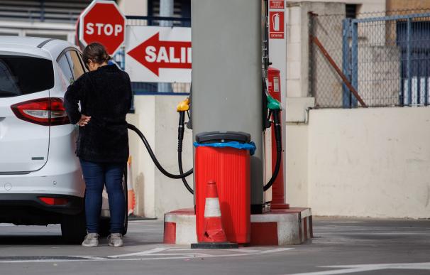 Una mujer reposta carburante en una gasolinera