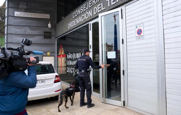 Un agente de la Policía Nacional entra con un perro a las dependencias de la Consejería de Obras Públicas de Cantabria