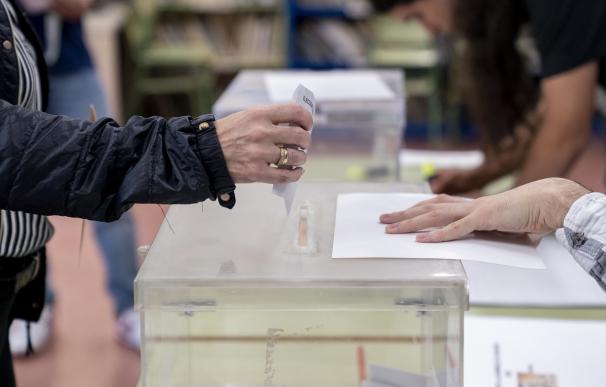 Una persona mete su voto en la urna en un colegio electoral