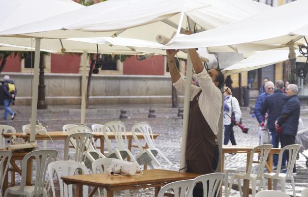 Un camarero pone los calefactores en una terraza en el puente del mes de diciembre en Sevilla