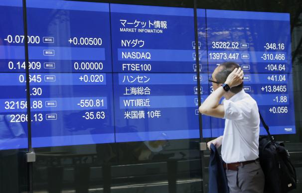 Un inversor pasea junto a una pantalla de bolsa en Tokio.