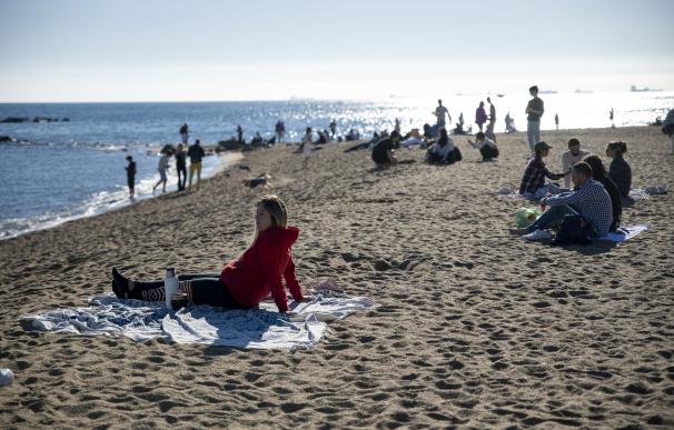 Varias personas disfrutan del sol y el calor en la playa de la Barceloneta, a 25 de diciembre de 2022, en Barcelona