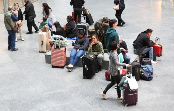 Numerosas personas con maletas esperan para viajar en la estación Almudena Grandes-Atocha Cercanías